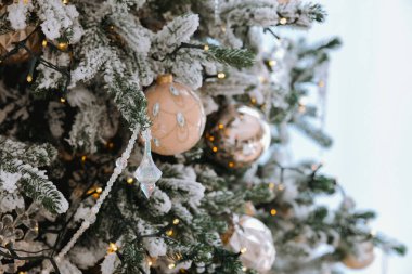 Noel ağacında zarif süsler ve sıcak ışıklarla süslenmiş buzlu dallar mevsimi için şenlikli ve rahat bir atmosfer yaratıyor..