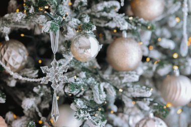 Gümüş süslemelerle dolu güzel dekore edilmiş bir Noel ağacı, narin kar taneleri ve yanıp sönen ışıklar bayram kutlamaları için mükemmel bir ortam yaratır..