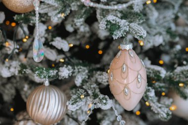 Güzel süslenmiş bir Noel ağacı parıldayan süslemelerle parıldıyor. Karlı dallar, tatil sezonunda parıldayan ışıkların ılık parıltısını tamamlayan neşeli bir atmosfer yaratıyor..