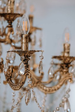 Karmaşık detaylar ve ışıldayan kristaller içeren güzel tasarlanmış bir klasik avize tavandan zarif bir şekilde sarkıyor ve çevreye sıcak bir parıltı saçıyor..