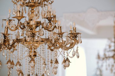 Karmaşık tasarımlar ve parlak kristaller içeren çarpıcı bir avize tavandan zarif bir şekilde sarkıyor, ışığı güzel dekore edilmiş odaya yansıtıyor..