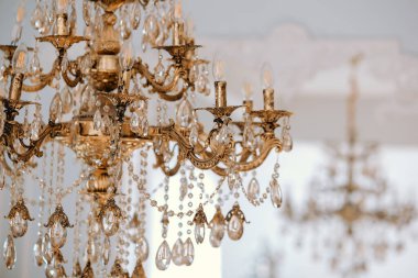 Zarif avize zarifçe tavandan sarkıyor, ışığı yakalayan parıldayan kristallerle süslenmiş. Karmaşık tasarımı aydınlık odaya biraz lüks katıyor..