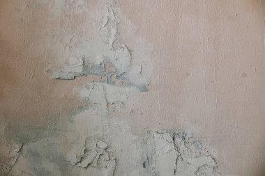 Duvarda çatlamış alçı bölgelerdeki aşınmalar yaşını ve ihmalini gösteriyor. Doku değişkenlik göstererek boya soyma ve altta yatan hasarı ortaya çıkarıyor..