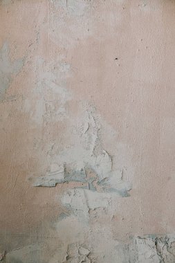 Duvar pürüzlü, pürüzlü bir alçı kaplama sergiliyor. Renk ve dokuda ince farklar var. Doğal ışık yüzeydeki kusurları ve hatları vurgular..