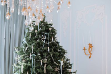 Zarif mumlar, kurdeleler ve ışıltılı süsler ile süslenmiş, güzel dekore edilmiş bir Noel ağacı, sıcak bir tatil atmosferi yaratıyor..