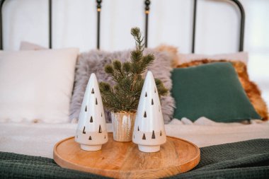 İki dekoratif seramik Noel ağacı ve küçük bir çam ağacı süslemesi rahat bir yatak süsler ve sıcak ve davetkar bir tatil atmosferi yaratır..