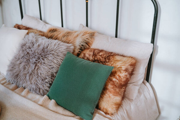 Красиво расположенная металлическая рама кровати демонстрирует массив плюшевых подушек в мягких текстурах и теплых тонах, создавая уютную и уютную атмосферу в спальне.