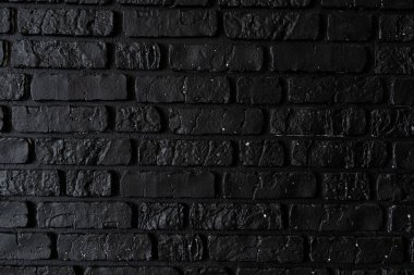 Zengin bir siyah tuğla duvar, iç mekanlara derinlik ve kontrastlık katan engebeli bir doku sergiliyor. Duvarın koyu tonu ortamın atmosferini arttırır..