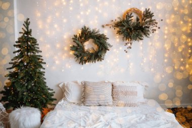 Sıcak ve davetkar bir yatak odası, parıldayan peri ışıkları ve tatil çelenkleriyle çevrili yumuşak yastıklı dekore edilmiş bir yatağı sergiliyor. Kış kutlamaları için mükemmel bir ortam yaratıyor..