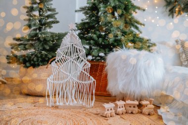 A charming holiday setup features a handmade tree and wooden train surrounded by soft textures and Christmas lights, creating a warm atmosphere perfect for the festive season. clipart