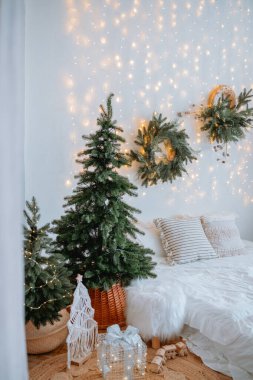 Büyüleyici bir yatak odası Noel süslemeleri ile süslenir. İçinde iki gür Noel ağacı, duvarda çelenkler ve parıldayan peri ışıkları bulunur. Sıcak bir tatil ortamı yaratır..