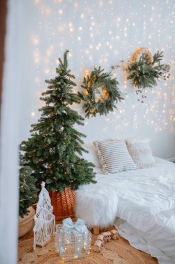 Bu rahat yatak odasında duvarlarda parıldayan ışıkların yanında güzel dekore edilmiş bir Noel ağacı var. Çelenkler ve hediyeler, kış için mükemmel şenlikli atmosferi tamamlıyor..