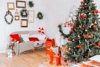 Oturma odası Noel için güzelce süslenmiş bir ağaç, battaniyeli rahat bir kanepe ve neşeli bir atmosfer yaratan tatil aksanıyla sıcacık dekore edilmiş..