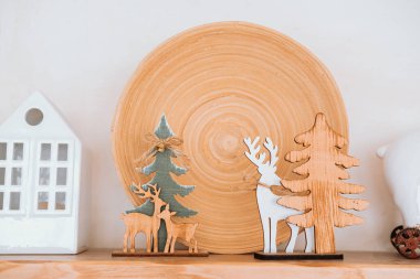 A charming display features wooden reindeer and trees set against a large rustic plate. The scene captures a cozy, festive atmosphere perfect for holiday decorating. clipart