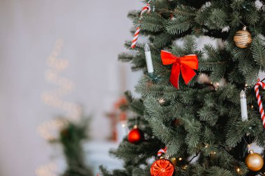 Güzel dekore edilmiş bir Noel ağacında canlı kırmızı bir fiyonk ve parıldayan süsler mevcuttur. Bayram kutlamaları için mükemmel, sıcak ve davetkar bir mekanda şenlikli bir atmosfer yaratır..