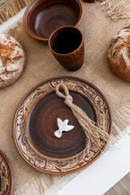 Güzel bir el yapımı tabak, kırsal ekmek ve dekoratif püskülle süslenmiş şenlik masası. Sıcak, davetkar atmosfer Noel 'in ve yeni yılın neşesini yansıtıyor..