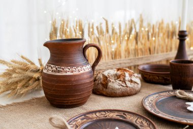 Güzel düzenlenmiş bir masa, kışın kutlamaları ve toplantılar için mükemmel sıcak ve davetkar bir atmosfer sunan kırsal çömlek ve dokuma elementleri barındırıyor..