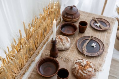 Güzelce düzenlenmiş bir tatil masasında geleneksel pişmiş yiyecekler, kırsal çömlekler ve sıcak bir mum sergileniyor. Sıcak bir kış havası Noel ve yeni yılı kutlamak için mükemmel..