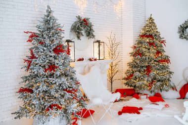 İki güzel dekore edilmiş Noel ağacı sıcak bir kış ortamında duruyor. Sıcak ışıklar, şenlikli bir dekor ve rahat koltuklar ile çevrili. Kutlama için keyifli bir tatil ortamı yaratıyor..