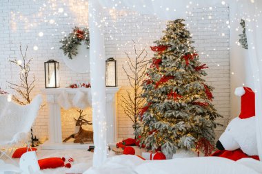 Kırmızı ve altın süslemelerle süslenmiş parlak ışıklandırılmış Noel ağacı sıcacık bir kış ortamında duruyor. Ağacı çevreleyen hediyeler, yeni yıl kutlamaları için şenlikli bir ortam yaratıyor..