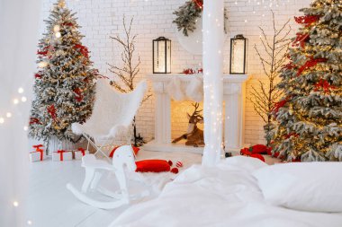 Sıcak kış ayinlerinde güzel dekore edilmiş Noel ağaçları, sıcacık bir şömine ve sallanan bir sandalye bulunur. Kırmızı ve beyaz hediye kutuları tatil sezonunun şenlikli atmosferine eklenir..