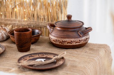 Kırsal bir çömlek seti, el yapımı kaseler, bir kap ve fincanların yer aldığı festival masasında güzelce düzenlenmiştir. Ortam sıcak ve davetkar. Tatil toplantıları ve kutlamalar için mükemmel..