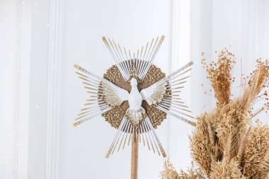 Güzel bir Noel ağacı tepesinde altın ışıklarla çevrili beyaz bir güvercin bulunur. Zarif dekorasyon, kış kutlamalarının şenlikli atmosferine cazibe katıyor..