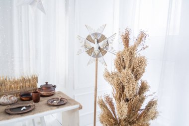 Kurumuş bitkilerle bir kış teması sunan dekoratif kurulum, rustik öğeler ve tatil öğeleriyle dolu bir masa, Noel ve yeni yılı kutlamak için ideal rahat bir atmosfer yaratıyor..