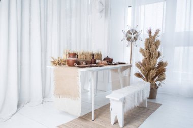 Güzel düzenlenmiş bir yemek masasında kırsal dekorasyonlar, sıcak çömlekler ve biraz yeşillik var. Sıcak kış ortamı Noel 'i kutlamak ve 2025 yılını kutlamak için mükemmel..