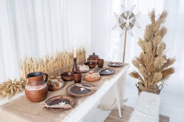 A cozy winter display features traditional pottery and dried floral arrangements on a white table. The festive setup creates a warm and inviting atmosphere for Christmas and New Year celebrations. clipart