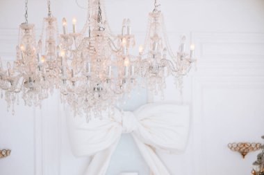 A stunning chandelier hangs gracefully from the ceiling, illuminating a winter celebration space adorned with elegant decor. clipart