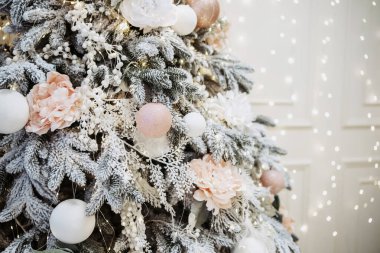 Kış harikalar diyarı atmosferiyle çevrili zarif beyaz ve pembe süslemelerle süslenmiş çarpıcı bir Noel ağacı. Arka planda neşeli bir dokunuş için yanıp sönen ışıklar var..