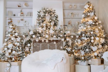 Sıcak kış dekorunda güzel dekore edilmiş Noel ağaçları, bir çelenk ve hediye kutuları var. Yumuşak ışıklandırma festival atmosferini güçlendirir ve kutlamalar için mükemmel bir tatil ortamı yaratır..