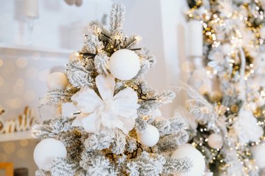 A beautifully decorated Christmas tree features white ornaments and an elegant bow, creating a festive atmosphere. The background gleams softly with warm lights, celebrating the holiday season. clipart