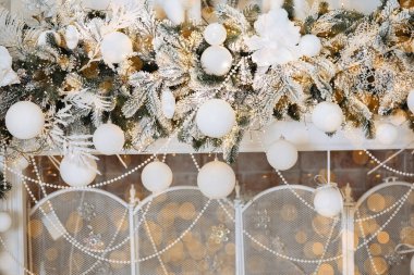 Beyaz süslemeler ve parlayan ışıklarla süslenmiş şenlikli yeşil çelenkler sıcak bir tatil atmosferi yaratır. Bu güzel dekor, Noel ve Yeni Yıl 'ın kış kutlaması ruhunu artırıyor..