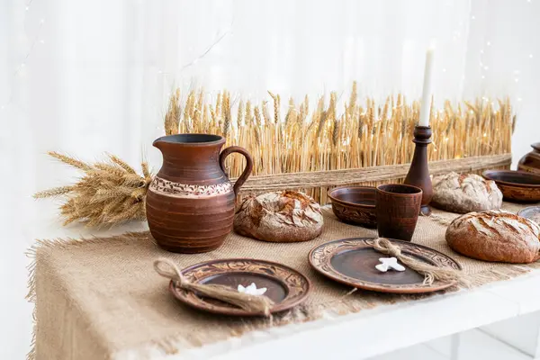 Güzel düzenlenmiş bir festival masasında kırsal çömlek, ekmek ve yemekler bulunur. Noel ve yeni yılı kutlamak için mükemmeldir. Sıcak atmosfer ve doğal dekor sıcak bir kış ortamı yaratır..