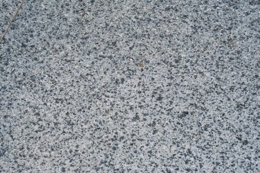 Granit bir yüzeyin detaylı bir görüntüsü eşsiz beneklerini ve desenlerini vurguluyor. Doğal ışık dokusunu vurgular ve güzel bir görsel etki yaratır. Bu gri taş genellikle yapım ve tasarımda kullanılır..