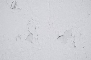 Beyaz bir duvarın yüzeyi çatlakları ve boyaları ortaya çıkarıyor, yaşını ve muhtemel nem hasarını gösteriyor. Doğal ışık, kusurların dokusuna derinlik katar..