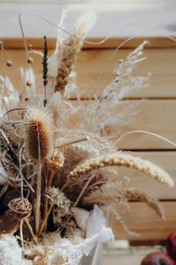 Kurumuş çiçek ve otlardan oluşan güzel bir koleksiyon kırsal bir ortamda ustalıkla düzenlenir. Yumuşak renkler ve dokular, materyallerin doğal güzelliğini vurgulayan sıcak ve davetkar bir atmosfer yaratıyor..