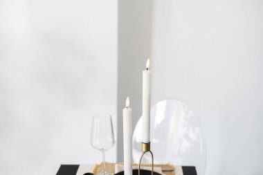 Mumlar ve şarap bardakları samimi bir toplantı için minimalist bir masaya dizilmiştir..