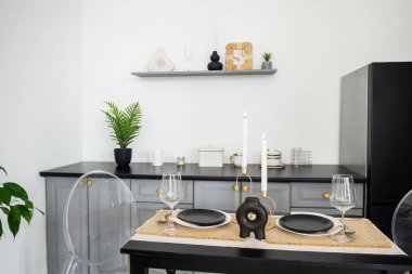 Çağdaş bir ortamda siyah tabaklar ve mumlarla şık bir yemek düzeni..