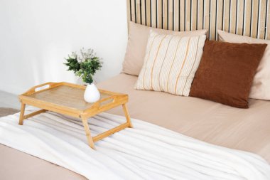 Yumuşak çarşaf ve yastıklar, rahat bir yatakta çiçeklerle dekoratif bir tepsi çerçeveler..