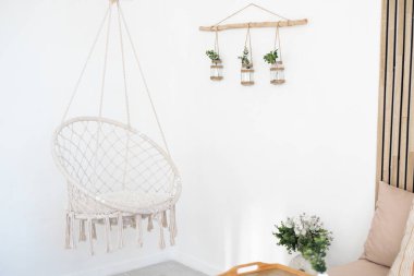 Sallanan sandalye ve duvara monte edilmiş bitki süslemelerinin yer aldığı rahat bir yer..