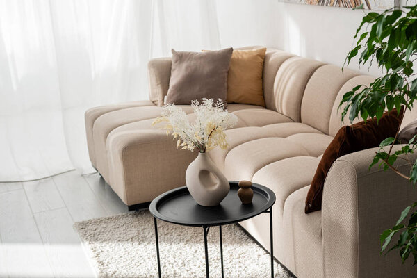 Стильная гостиная имеет плюшевый секционный диван и элегантные предметы декора.