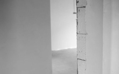 Pürüzsüz beyaz duvarları ve yumuşak ışığı olan minimalist bir alanda dar bir geçit.