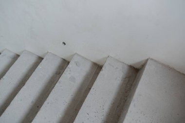 Modern bir iç mekanda düz beyaz bir duvara doğru somut adımlar yükseliyor..