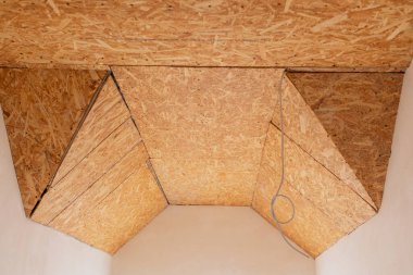 Eşsiz açısal tavan tasarımı bir inşaat ortamında ahşap paneller sergiliyor.