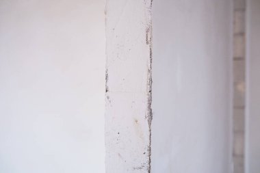 Yumuşak ışık, minimalist bir alanda alçı duvar köşesinin dokusunu güçlendirir..