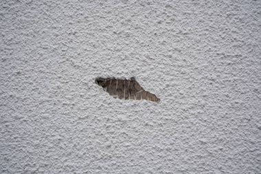 Duvarın bir parçası eksik. Altında elektrik kabloları ve pürüzlü yüzey var..