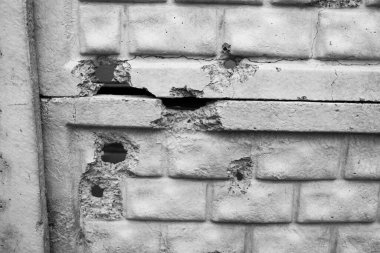 Şehir ortamında çatlakları ve hasarları olan bir duvarın yakın görüntüsü.